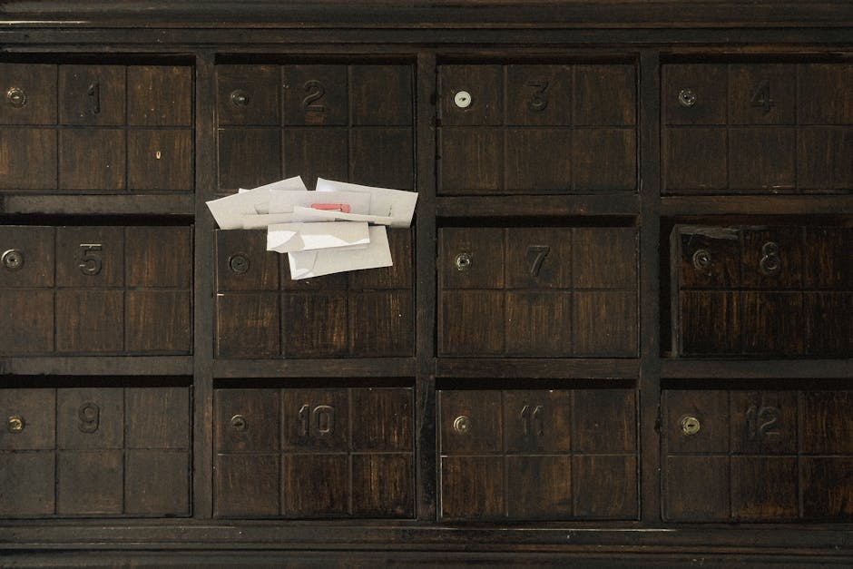 Old wooden mailbox showing numbered slots and inserted letters.